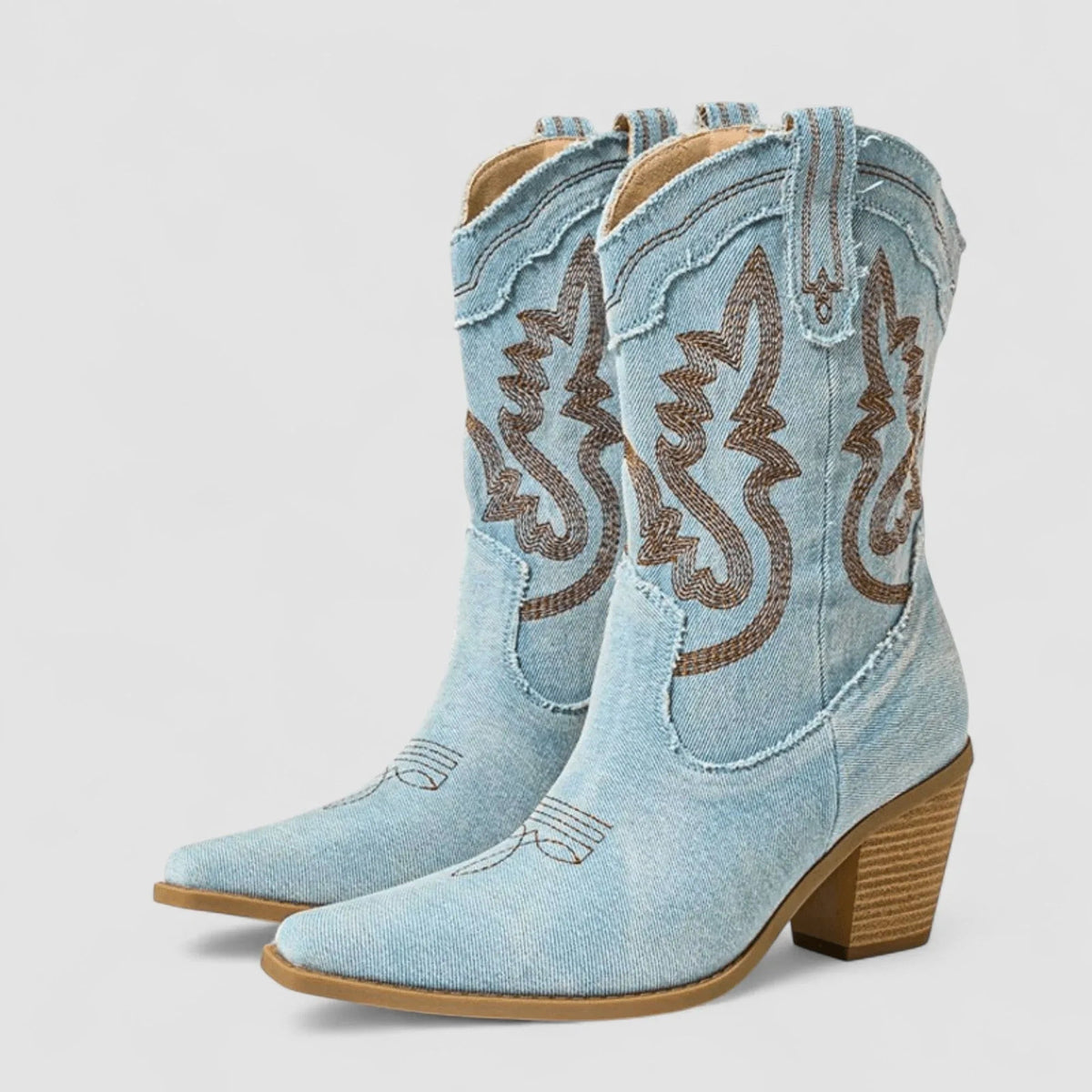 Light blue denim ankle boots with brown embroidered swirl detail, side view