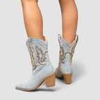 Light blue denim ankle boots with brown embroidery and stacked block heel, rear view