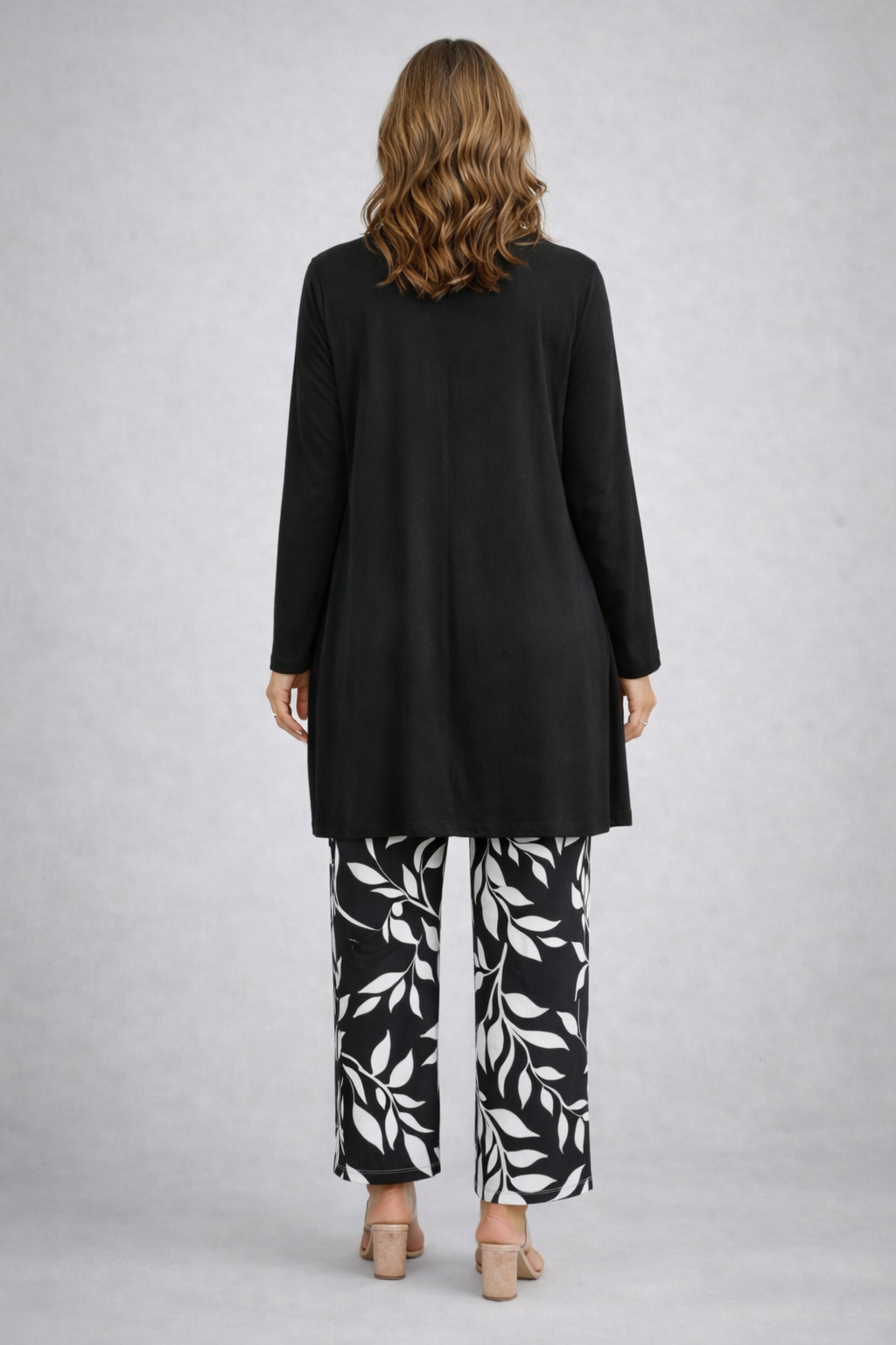 Black long cardigan and top over leaf-print pants, back view