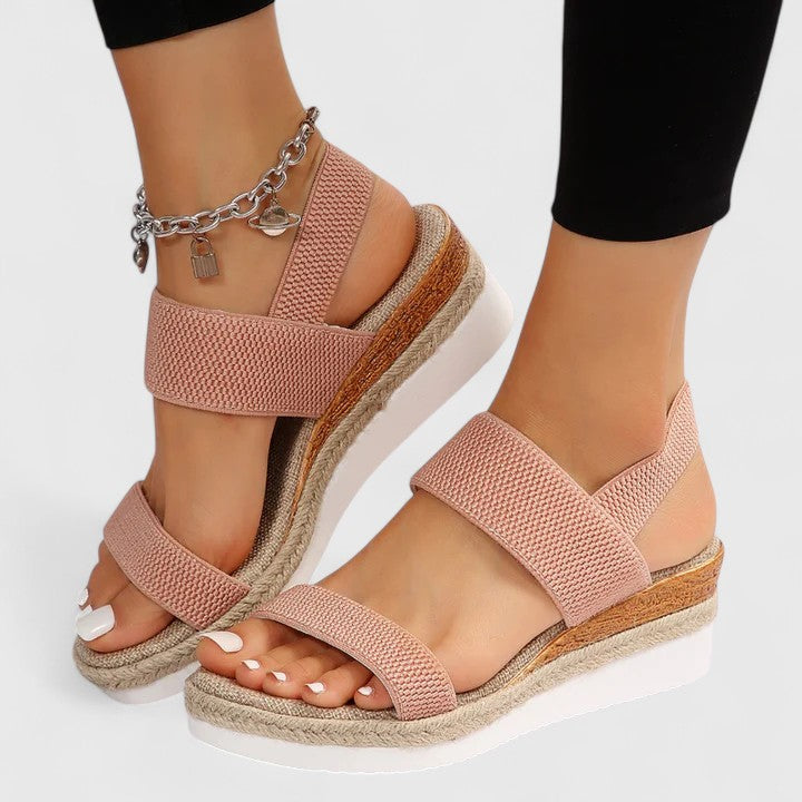 Blush pink orthopedic sandals with wide straps, tan espadrille sole, and chain ankle charm