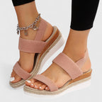 Blush pink orthopedic sandals with wide straps, tan espadrille sole, and chain ankle charm